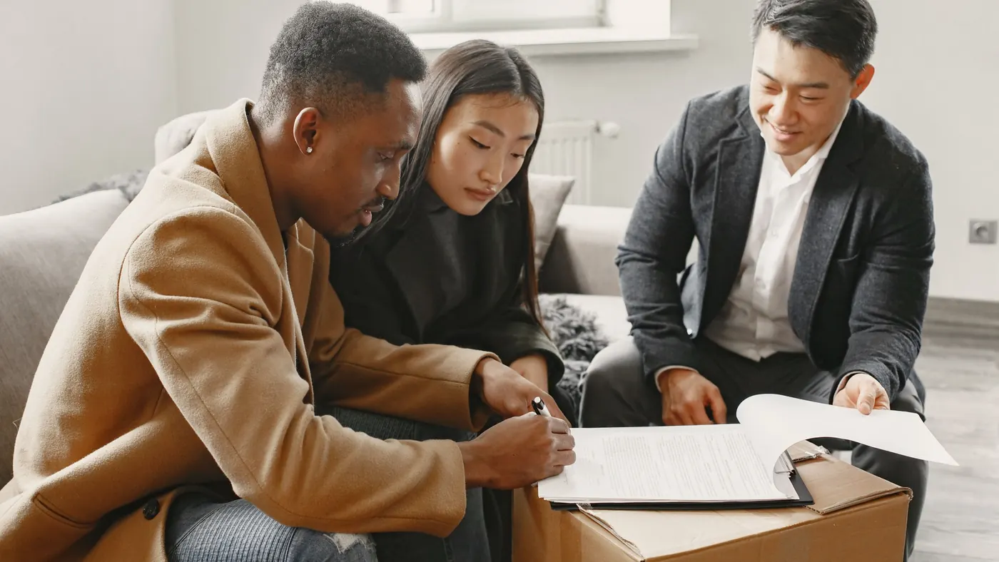 Buyers reviewing and signing a document with an advisor, illustrating a buyer representation agreement in Ontario