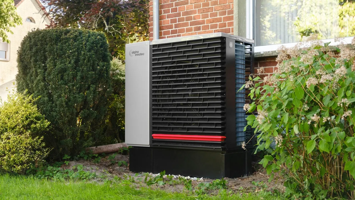 Air source heat pump unit installed beside a brick house, illustrating cold climate heat pumps in Oro-Medonte