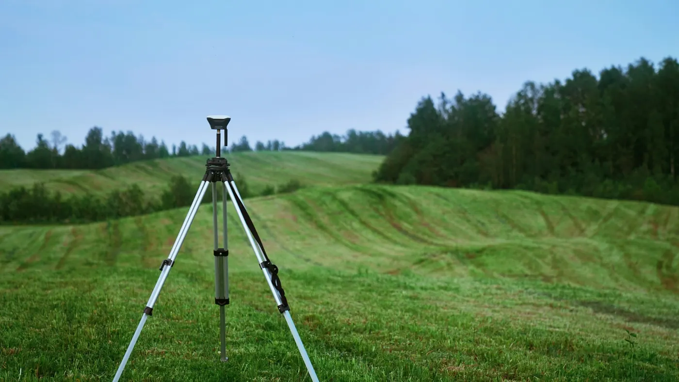 Surveyor's total station on a tripod in a rural field, illustrating property surveys for Midland homebuyers