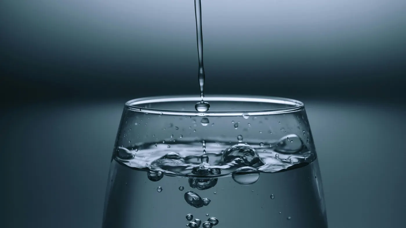 Clear water being poured into a glass, illustrating well water testing and treatment for Oro-Medonte homes