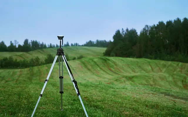 Surveyor's total station on a tripod in a rural field, illustrating property surveys for Midland homebuyers
