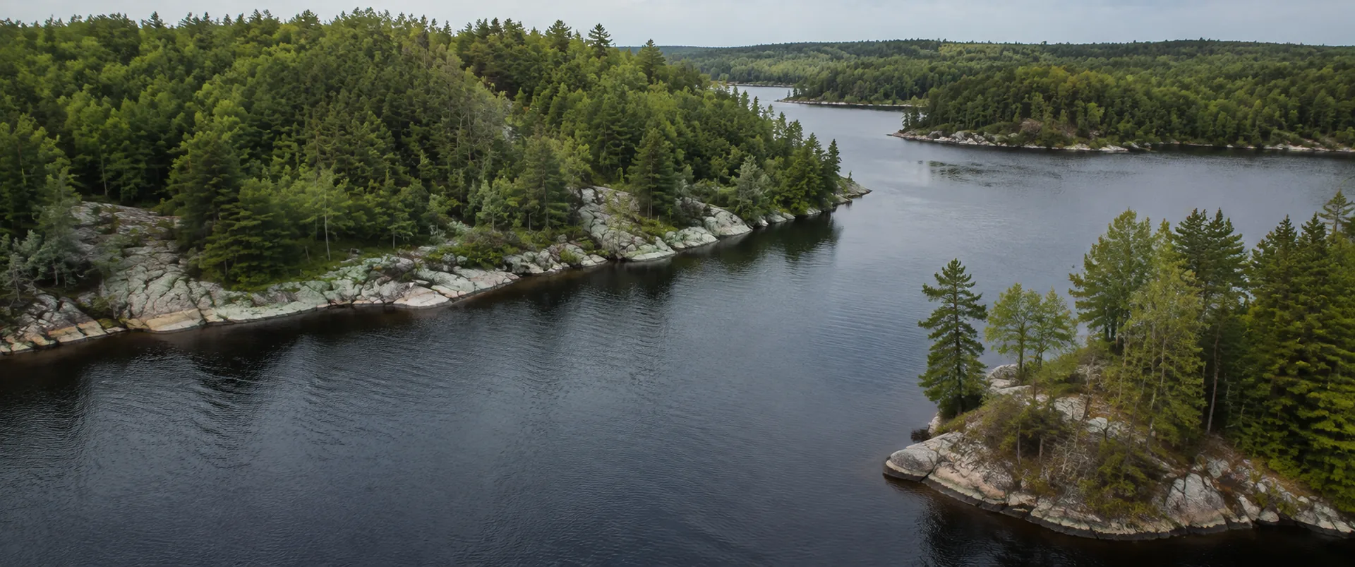 Rocky, pine-lined shoreline and open water in Ontario cottage country, late summer
